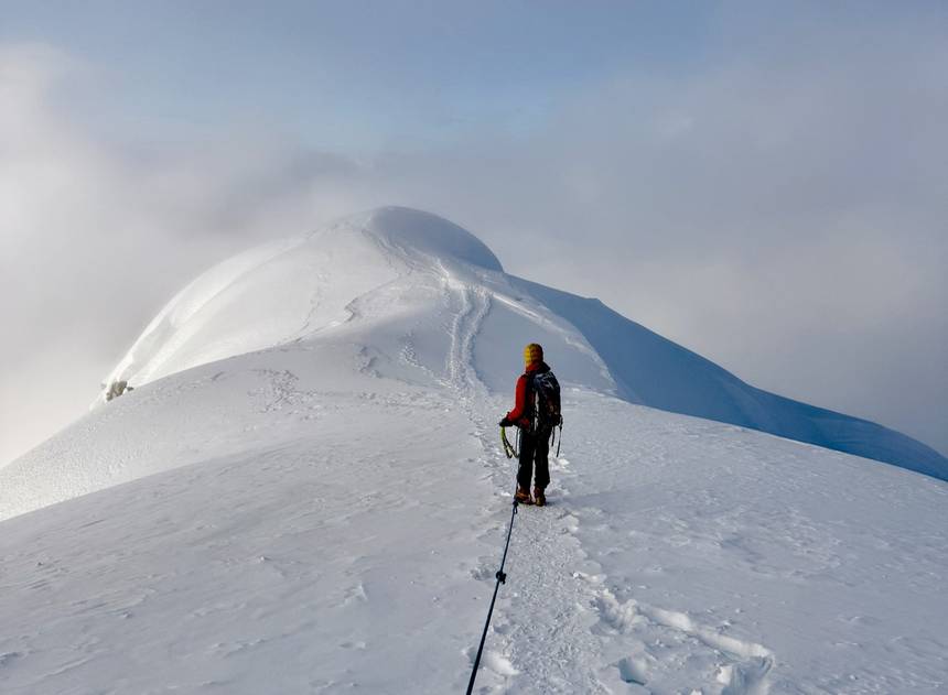 A climber on a corniced summit ridge in cloud, Cordillera Blanca
